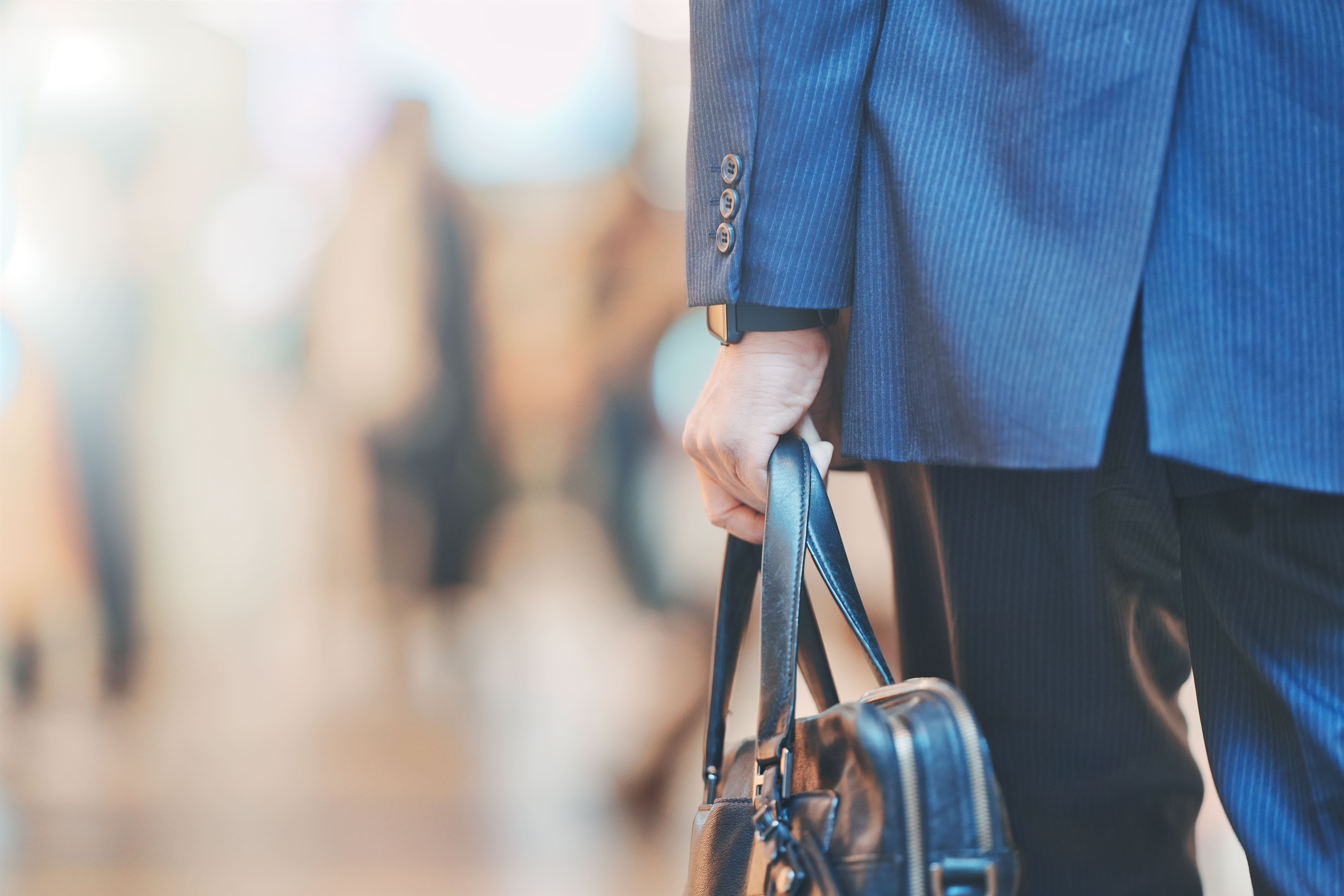 スーツを着た男性がバックを持っている手元が写っています